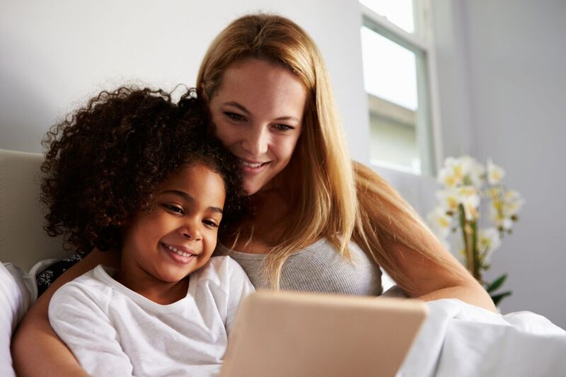 Caucasian-mum-and-black-daughter-use-tablet-in-bed,-close-up-524156918_5184x3456